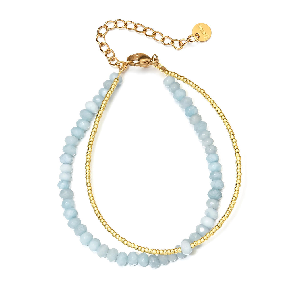 Bracelet double rang avec perles facettées bleu ciel et chaîne fine dorée ajustable.