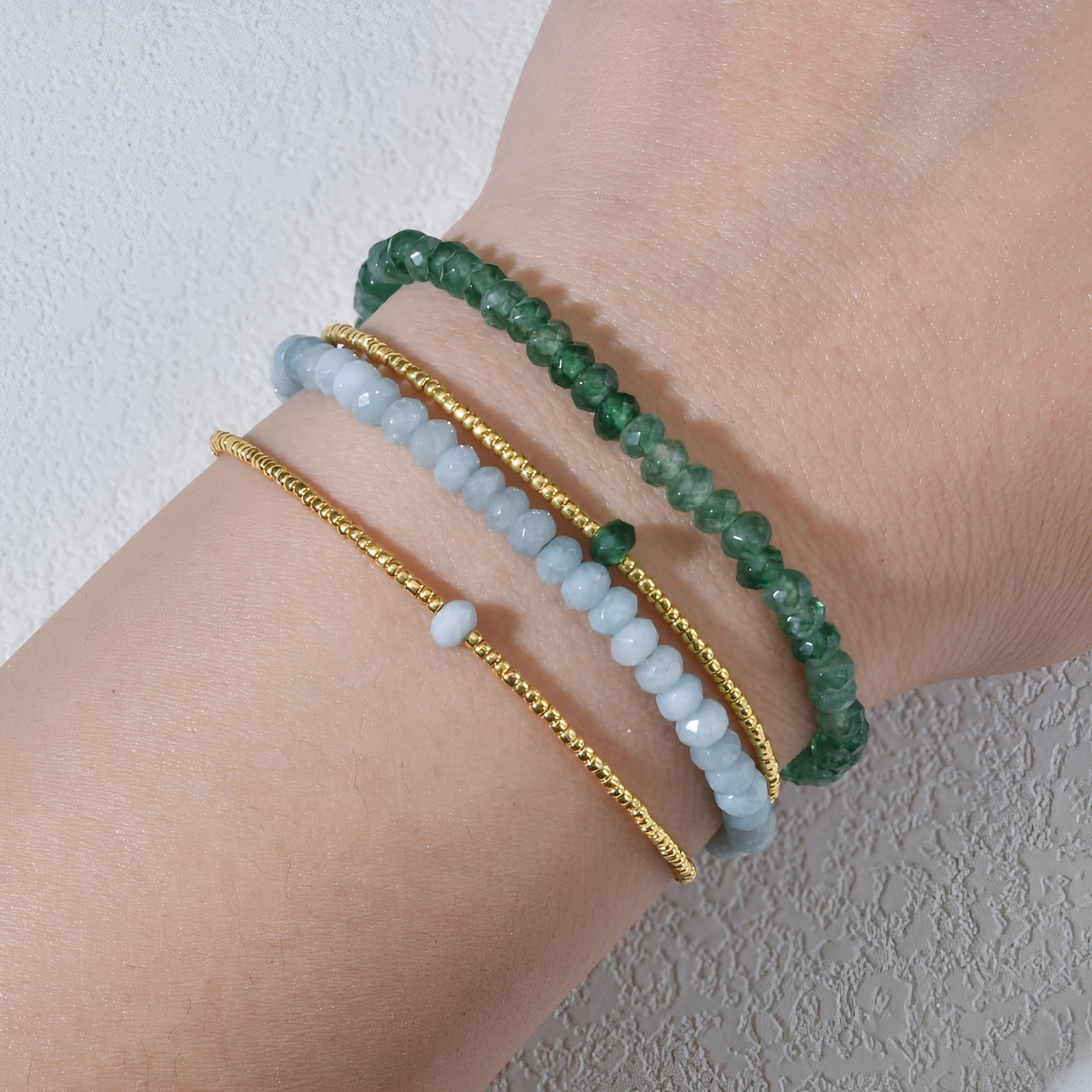 Bracelet double rang avec perles facettées vertes et blanches, billes dorées fines, design élégant et coloré.