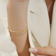 Bracelet double rang en titane plaqué or, lignes fines et élégantes sur poignet féminin.