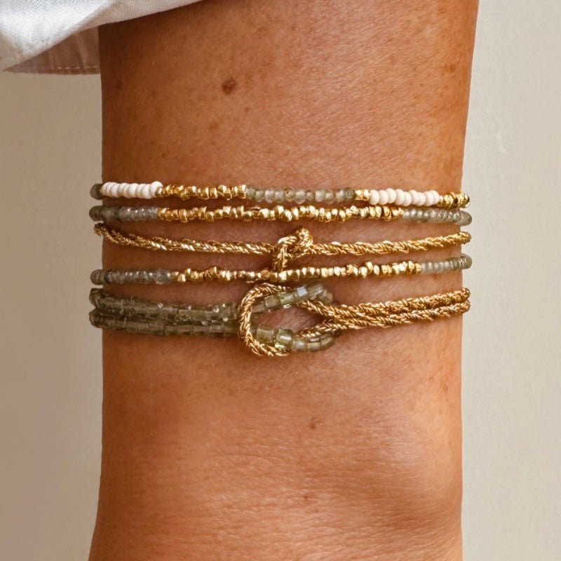 Bracelet double rang or torsadé avec perles blanches nacrées et fermoir mousqueton élégant.