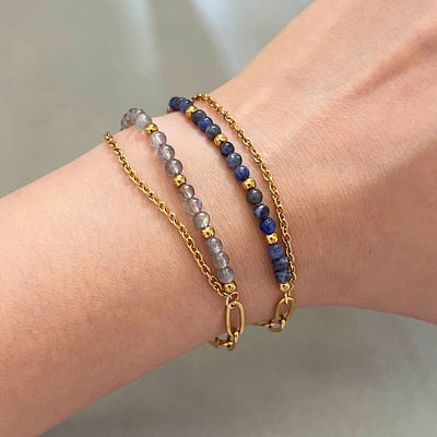 Bracelet double rang avec perles bleues et grises en pierres naturelles, chaîne fine dorée et fermoir mousqueton.