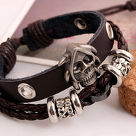 Bracelet double-rangs en cuir noir avec tête de mort en métal et détails tressés marron.