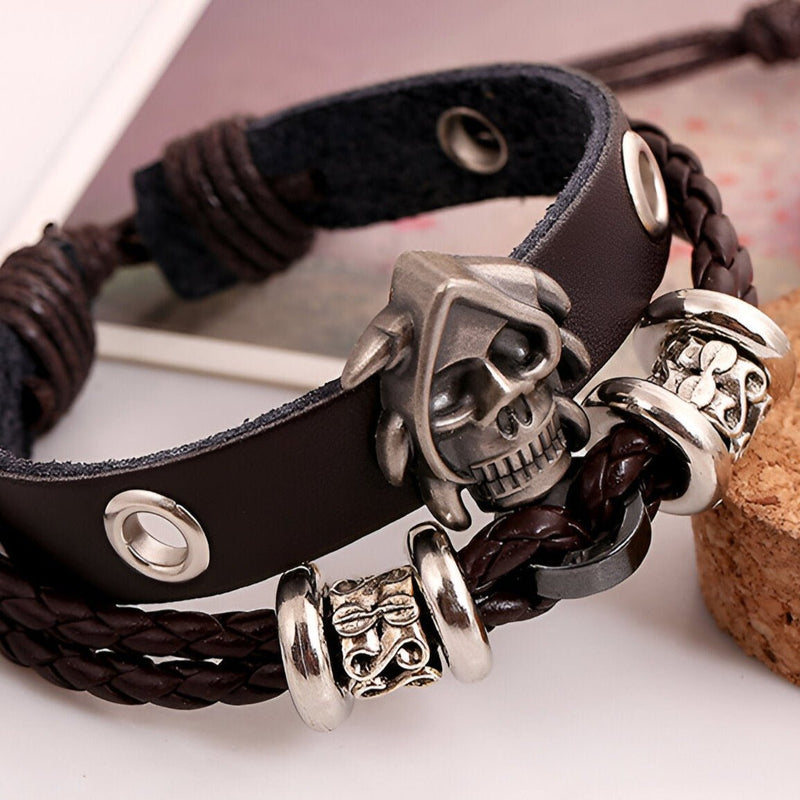 Bracelet double-rangs en cuir noir avec tête de mort en métal et détails tressés marron.