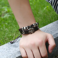 Bracelet double rangs en cuir noir avec tête de mort en métal argenté et perles décoratives.