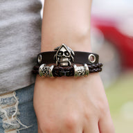Bracelet double-rangs en cuir noir avec tête de mort métal argenté et détails tressés.