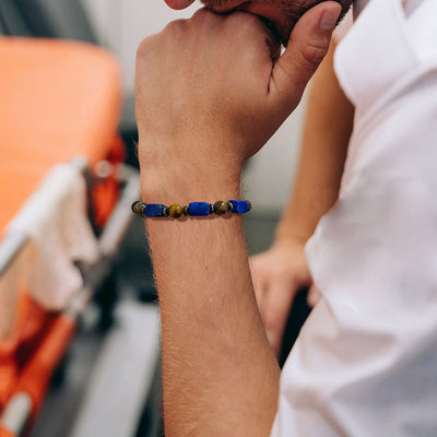 Bracelet élastique masculin en pierres volcaniques noires et gemmes bleues avec perles dorées élégantes.