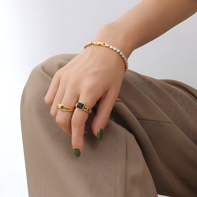 Bracelet fin en titane doré avec pierres de zircon scintillantes porté au poignet.