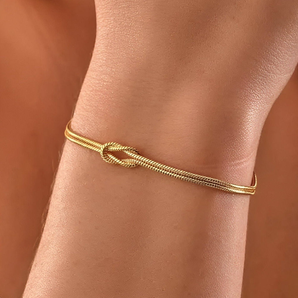Bracelet fin en acier inoxydable doré avec nœud central élégant, modèle Sarai pour femme.