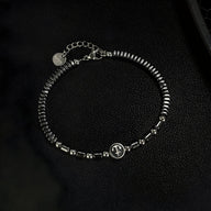 Bracelet homme en acier inoxydable avec perles d'hématite noire et charm ancre argenté.