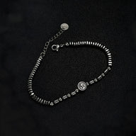 Bracelet homme en acier inoxydable et hématites noires avec charm ancre argenté, finition brillante.