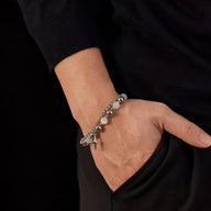 Bracelet argenté en acier inoxydable avec perles d'œil de chat porté au poignet d'homme.