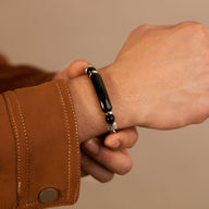 Bracelet homme acier inoxydable avec perle œil de tigre noir et détails argentés.