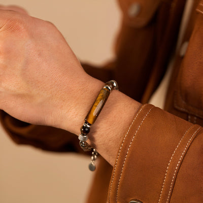 Bracelet homme en acier inoxydable argenté avec perles d’œil de tigre marron et noirs, détail pendentif rond.