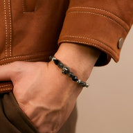Bracelet masculin en acier inoxydable argenté avec pierres noires et tête de lion centrale détaillée.