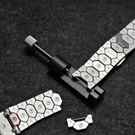 Bracelet en acier inoxydable argenté avec maillons hexagonaux, outil d’ajustement noir et argenté.