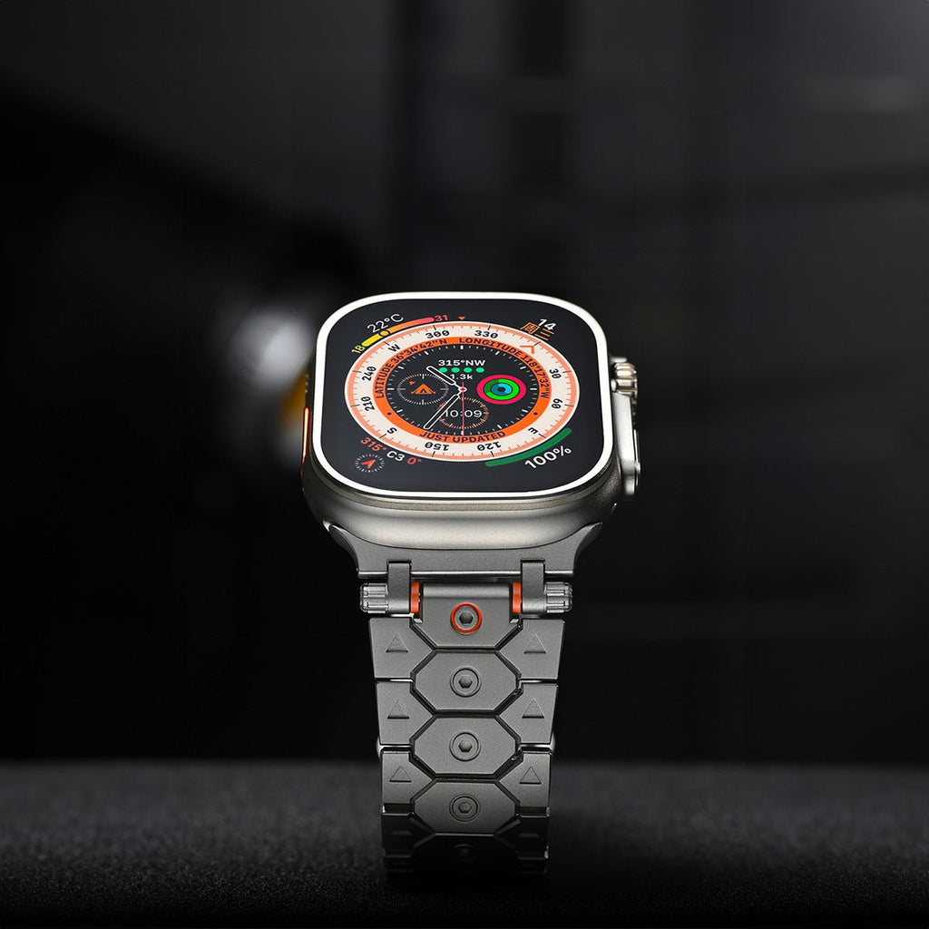 Bracelet en acier inoxydable gris à maillons hexagonaux, accents orange, pour Apple Watch.