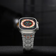 Bracelet en acier inoxydable gris à maillons hexagonaux, accents orange, pour Apple Watch.