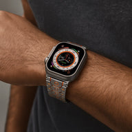 Bracelet acier inoxydable argent avec détails orange, ajustable pour Apple Watch, style Halo, porté au poignet.