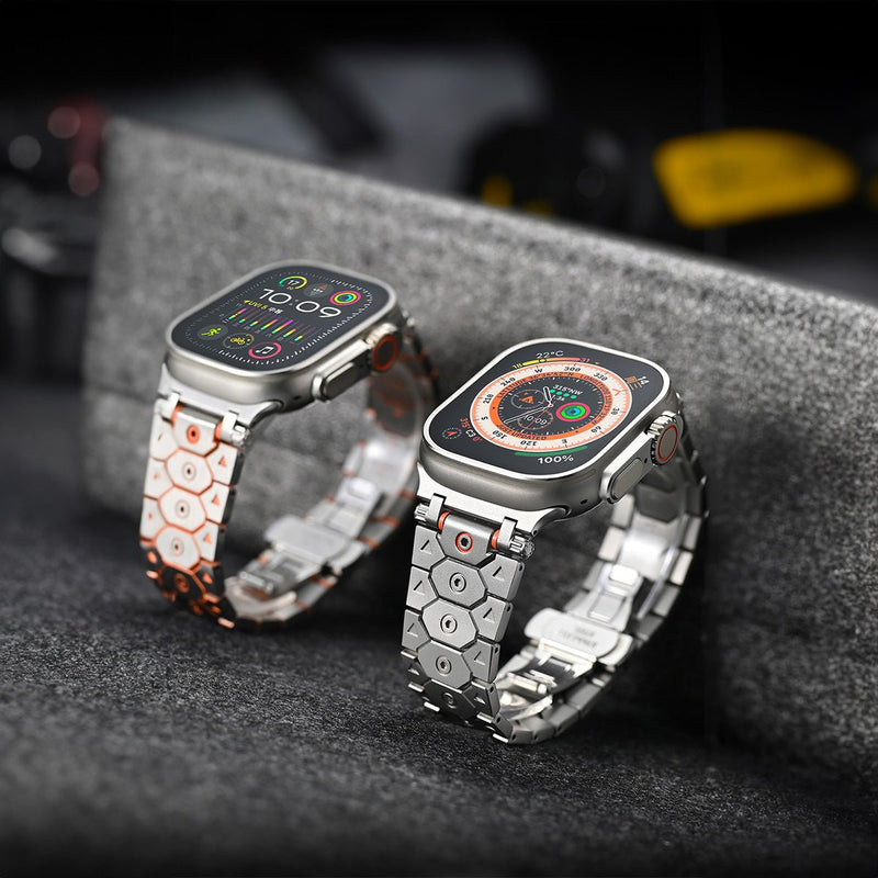 Deux montres Apple avec bracelets en acier inoxydable ajustables, motifs hexagonaux argent et noir, détails orange et or.