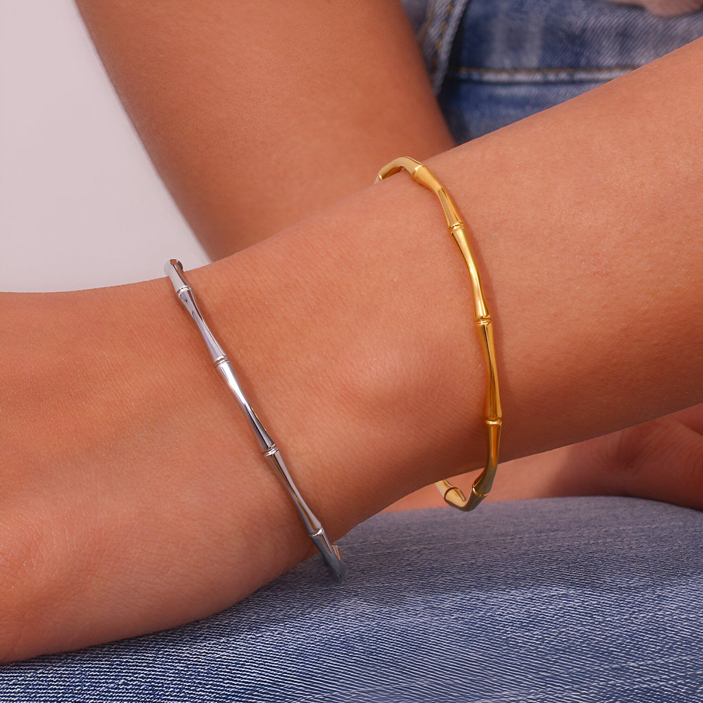 Bracelet fin en acier inoxydable plaqué or 18 carats style bambou porté au poignet femme, aussi en argent visible.
