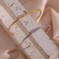 Bracelet rigide en acier inoxydable design bambou, plaqué or 18 carats et argent, finition lisse et brillante.