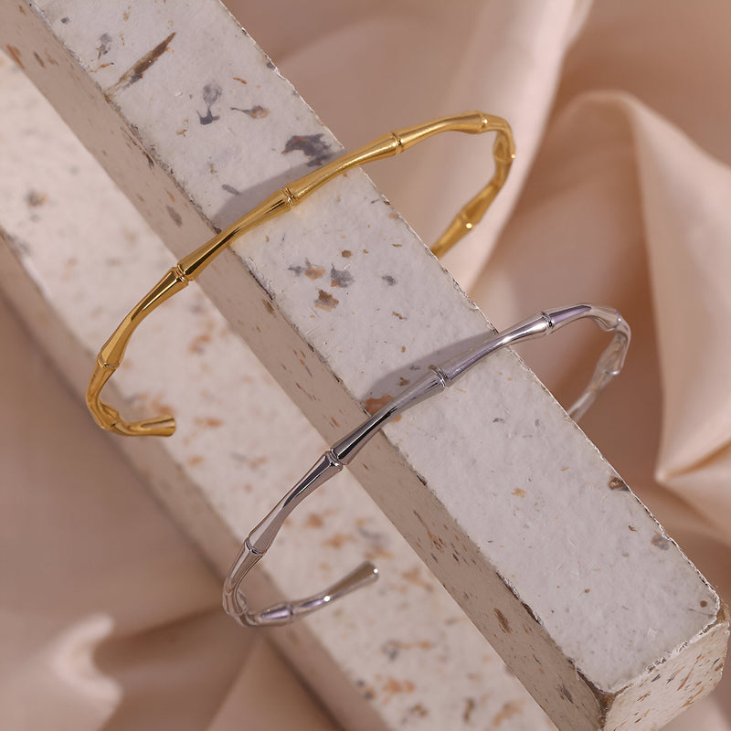 Bracelet rigide en acier inoxydable design bambou, plaqué or 18 carats et argent, finition lisse et brillante.
