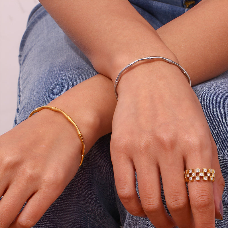 Bracelet fin en acier inoxydable doré, motif bambou élégant porté au poignet.