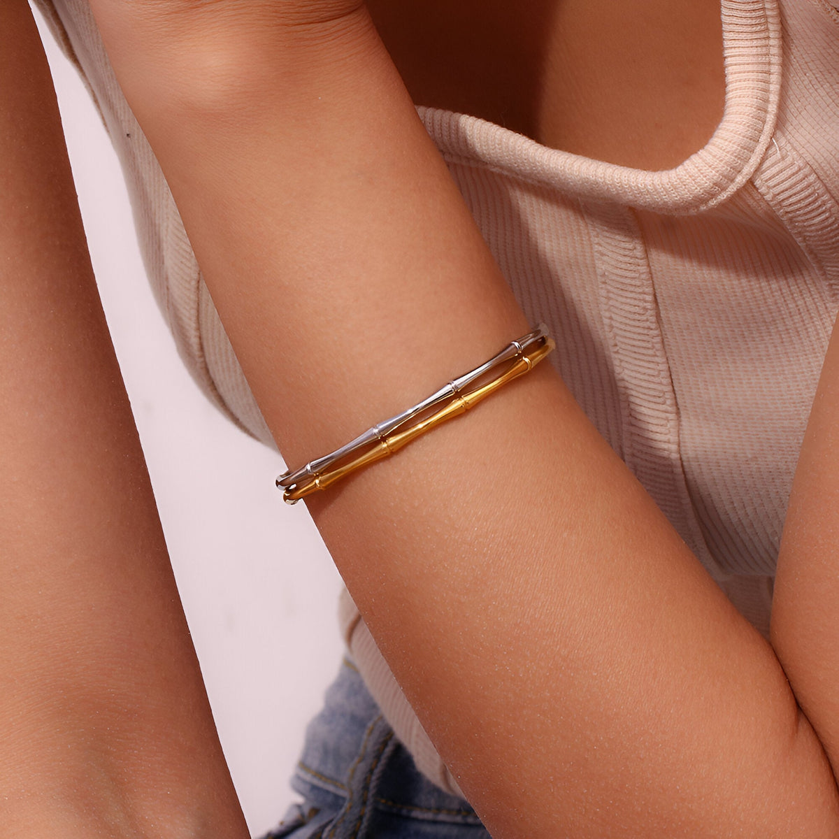 Bracelet fin en acier plaqué or 18 carats avec design bambou, porté au poignet féminin.