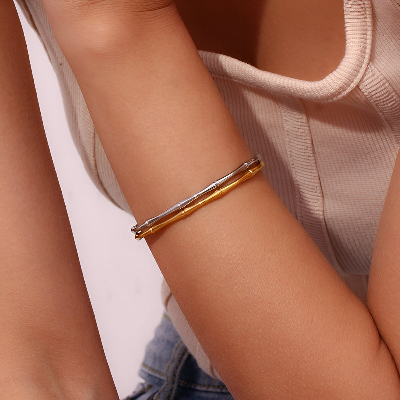 Bracelet fin en acier plaqué or 18 carats avec design bambou, porté au poignet féminin.