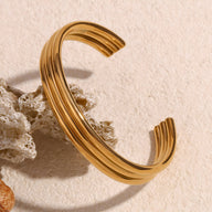 Bracelet jonc ouvert en acier inoxydable plaqué or 18 carats avec finition nervurée brillante.