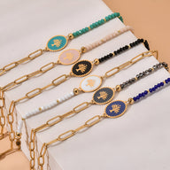 Bracelets en acier inoxydable avec arbre de vie coloré sur médaillon ovale, chaînes dorées et perles multicolores.