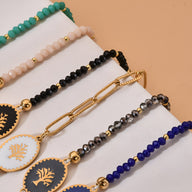 Bracelets pour femme en acier inoxydable multicolores avec pendentifs arbre de vie blancs et détails dorés.