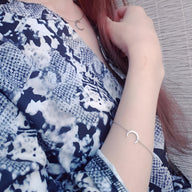 Bracelet fin en acier inoxydable or avec pendentif lune sur le poignet féminin.