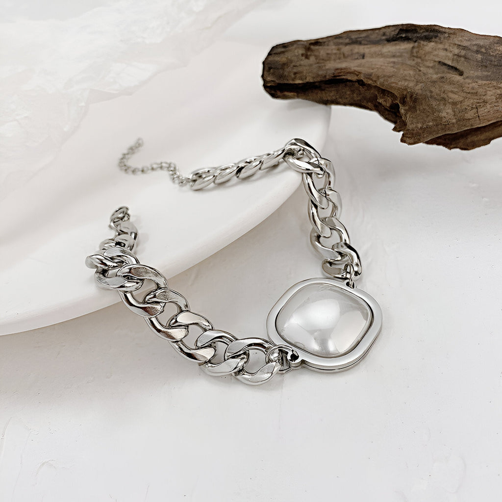 Bracelet homme en acier inoxydable argenté avec chaîne épaisse et plaque ovale lisse et brillante.