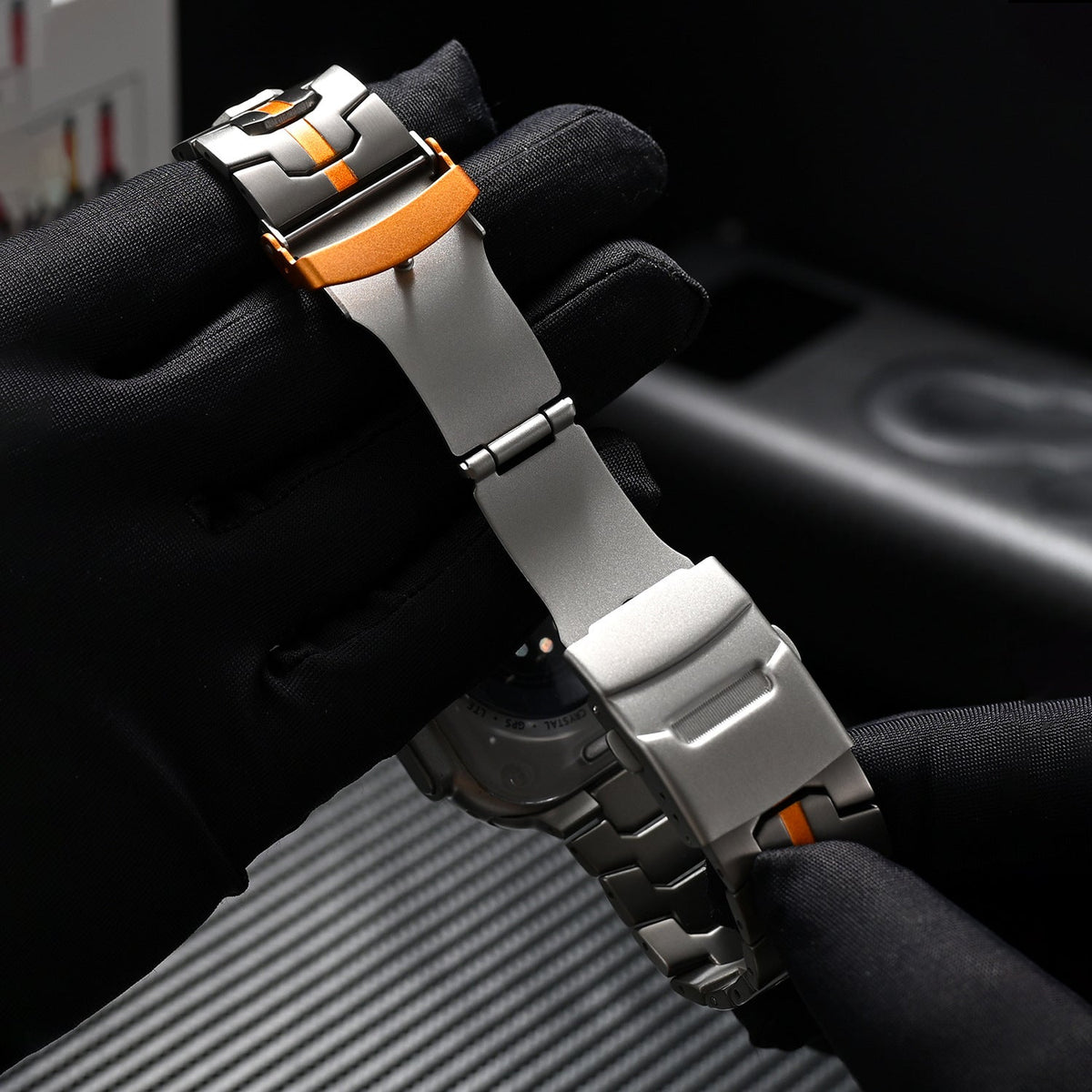 Bracelet pour Apple Watch en acier inoxydable gris clair et orange, ajustable, design robuste et moderne.