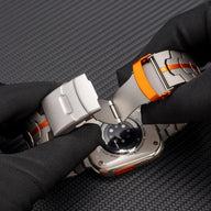 Bracelet Apple Watch en acier inoxydable gris avec insert orange, fermoir déployant solide.