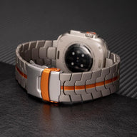 Bracelet en acier inoxydable gris avec bande orange et fermoir ajustable pour Apple Watch.