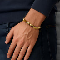 Bracelet homme en acier inoxydable doré, maille rolo épaisse, finition brillante, porté au poignet.