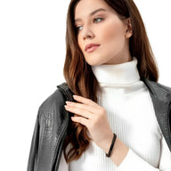 Bracelet en maille spiga noire en acier inoxydable porté sur poignet féminin, style moderne et épuré.