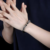 Bracelet homme en argent massif avec double tête de dragon sculptée, finition noire et argentée.