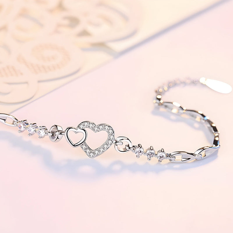 Bracelet en argent massif pour femme avec charm double cœur pavé de pierres brillantes.