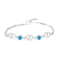 Bracelet en argent avec chaîne fine, charms cœurs et pierres bleues étincelantes.