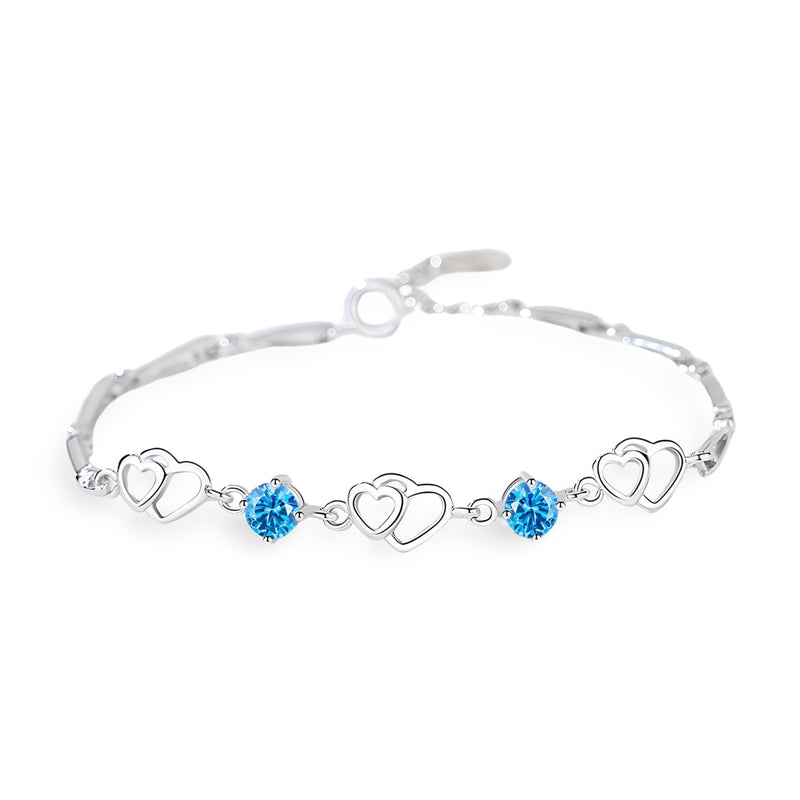 Bracelet en argent avec chaîne fine, charms cœurs et pierres bleues étincelantes.