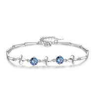 Bracelet en argent avec trèfles à quatre feuilles et pierres bleues serties sur chaîne fine.