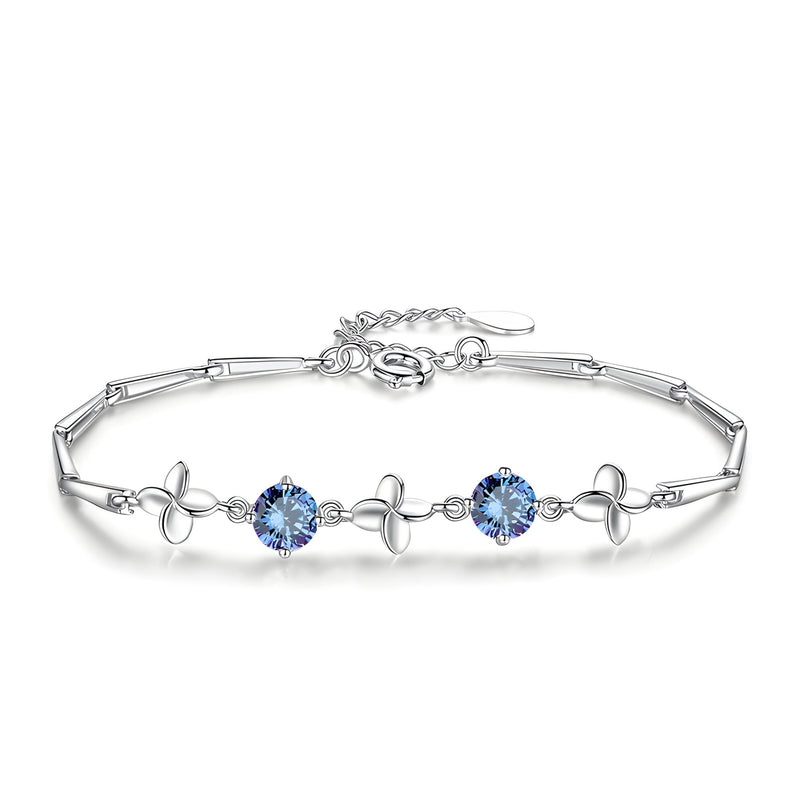 Bracelet en argent avec trèfles à quatre feuilles et pierres bleues serties sur chaîne fine.