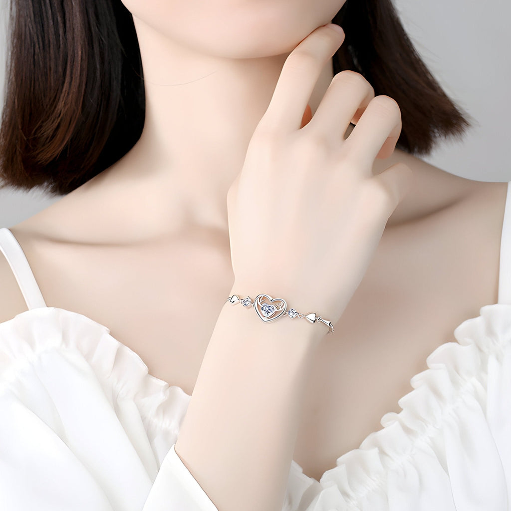 Bracelet en argent fin avec pendentif cœur ajouré et cerf délicat, style élégant féminin.