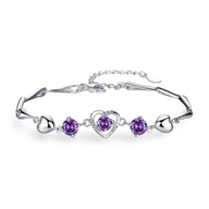 Bracelet en argent avec charmes cœur et pierres violettes serties, style délicat pour femme.