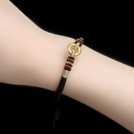 Bracelet fin noir en argent sterling avec cercle doré et nœud coulissant rouge, noir et beige.