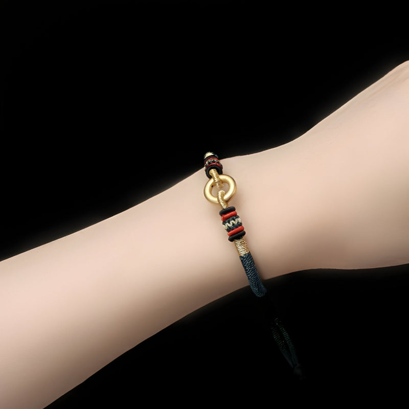 Bracelet en argent sterling avec cercle doré et cordon noir ajustable sur poignet féminin.