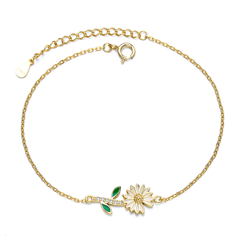 Bracelet fin en or avec pendentif marguerite détaillé et feuilles émaillées vertes.